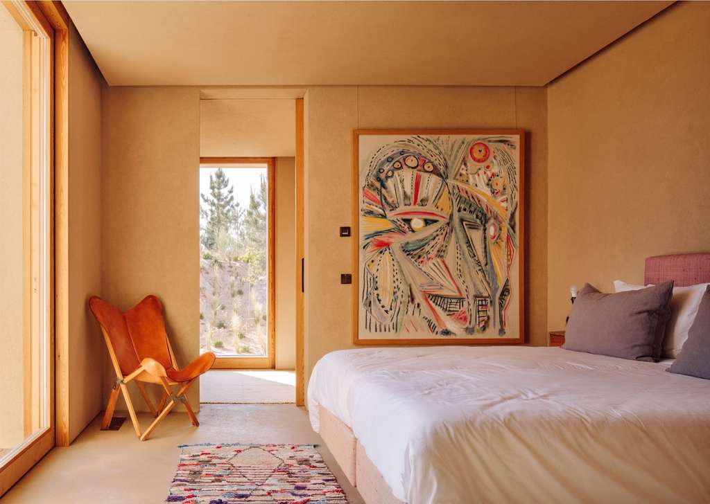 Bedroom with a large colorful face painting and a leather butterfly chair